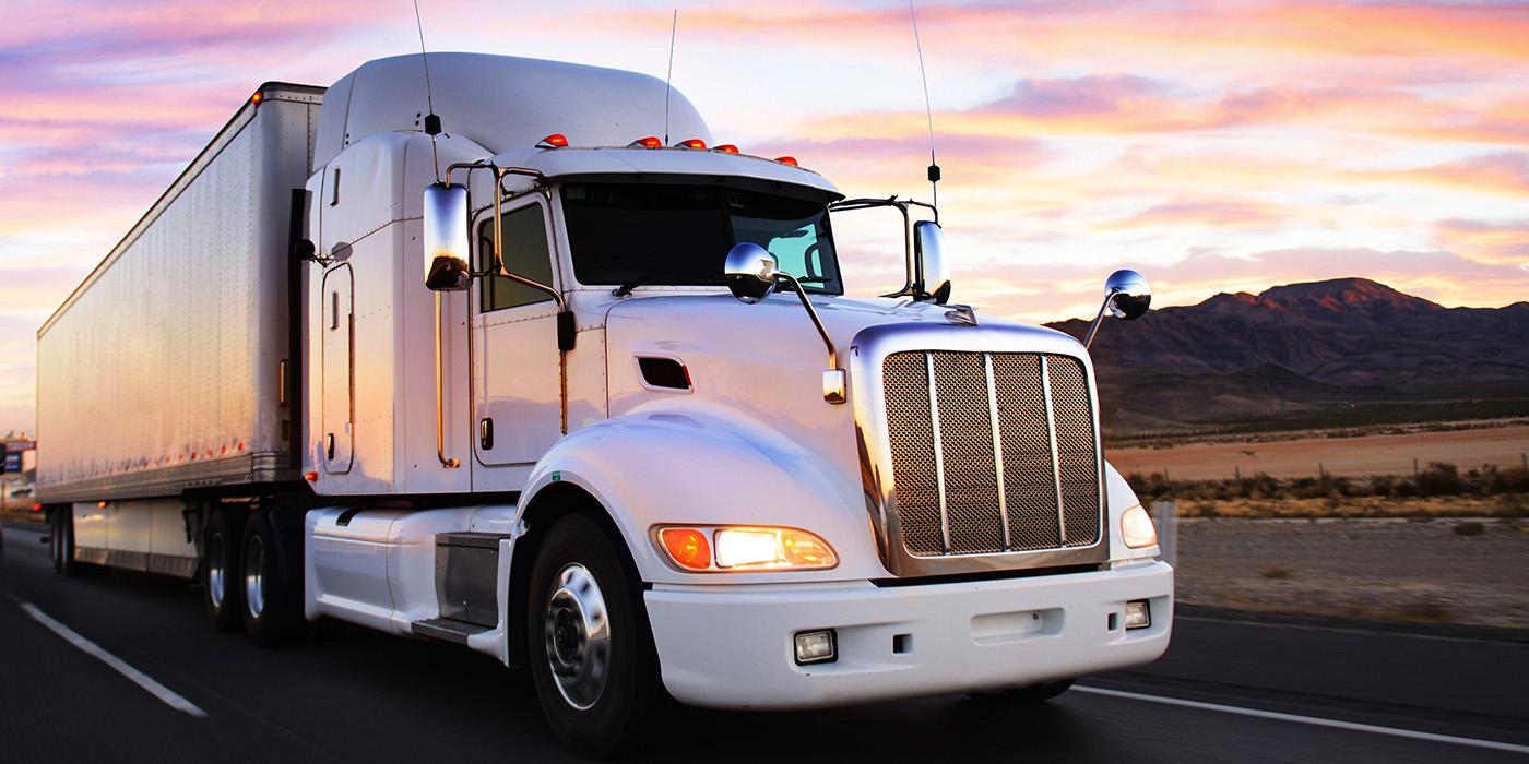 Semi truck driving on a road at sunset