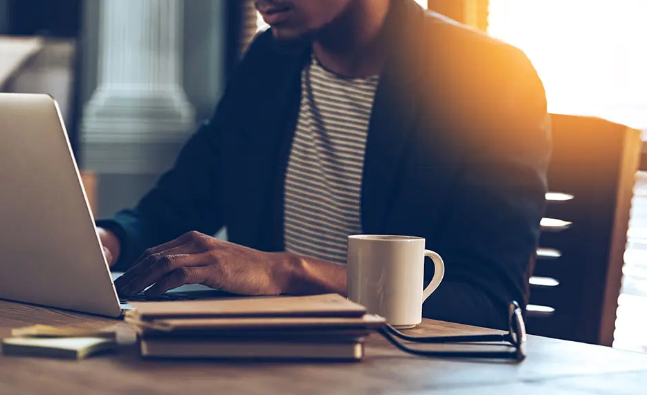 Individual working on a computer with light coming in the background